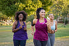 Tres mujeres realizan una sesión de running al aire libre en un parque, corriendo juntas con ropa deportiva durante un día soleado.