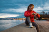 Mujer revisando los datos de su reloj deportivo después de entrenar al aire libre junto al agua durante el atardecer.