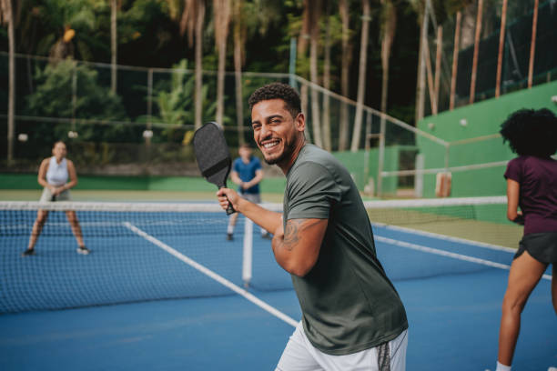 Jugador practicando pickleball al aire libre en una pista deportiva.
