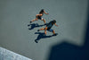 Vista aérea de dos personas corriendo sobre una pista deportiva, con sus sombras proyectadas en el suelo.